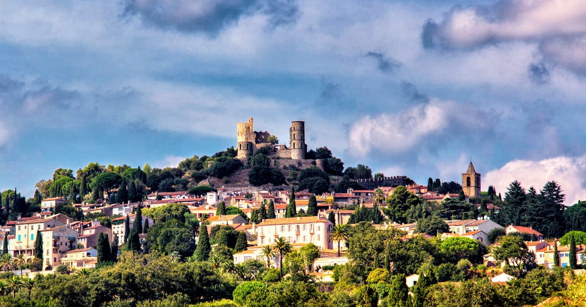 Vue aérienne d'un village perché provençal aux toits ocres, baigné par la lumière douce du lever du soleil, sans touristes apparents.